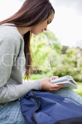 Young smiling student doing her homework in a park