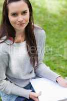 Young calm girl sitting in a park while holding school books
