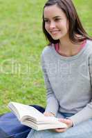 Smiling young woman looking away while holding a book