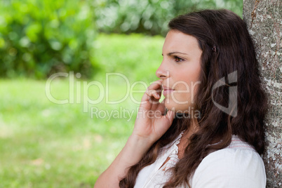 Young serious woman talking on the phone while leaning against a