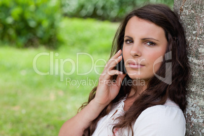 Young serious woman calling with her mobile phone while sitting