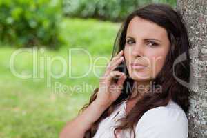 Young serious woman calling with her mobile phone while sitting