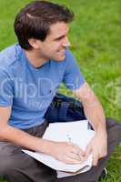 Young smiling man looking away while working on the grass