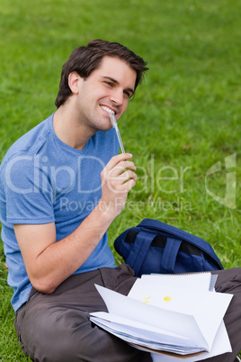 Young smiling man working while sitting on the grass