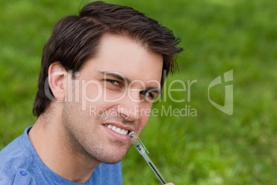 Young thoughtful man looking at the camera while holding his pen