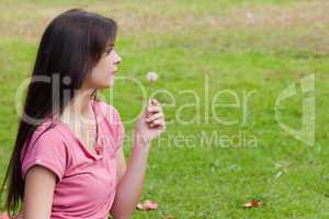 Young woman holding a dandelion while standing in the countrysid