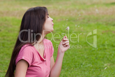 Young relaxed woman blowing a dandelion