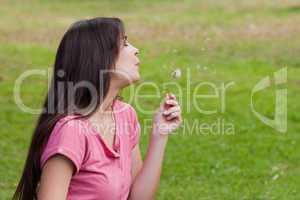 Young relaxed woman blowing a dandelion