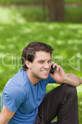 Young smiling man calling with his cellphone while sitting in a