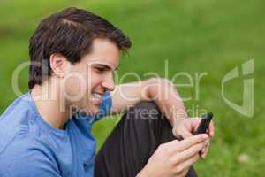 Young man sending a text with his cellphone while sitting on the