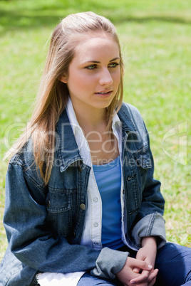 Young blonde girl looking towards the side while sitting down in