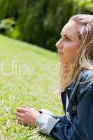 Young serious woman looking ahead while lying on the grass