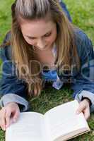 Young relaxed girl lying on the grass while reading a book