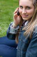 Young smiling girl talking on the phone while sitting down in a