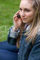 Young blonde woman calling with her mobile phone while sitting i
