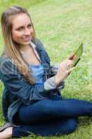 Young happy girl looking at the camera while using her tablet co