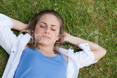 Young relaxed girl napping on the grass while placing her hands