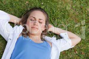 Young relaxed girl napping on the grass while placing her hands