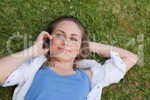 Young relaxed blonde girl lying on her back while talking on the