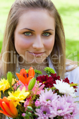 Young relaxed girl holding a bunch of flowers in a public garden