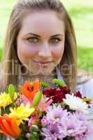 Young relaxed girl holding a bunch of flowers in a public garden