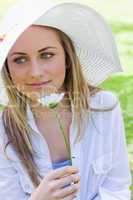 Young peaceful girl holding a white flower in a park