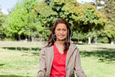 Young woman smiling in an area surrounded by grass and trees