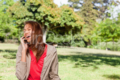 Young woman enthusiastically laughing while on the phone in an o