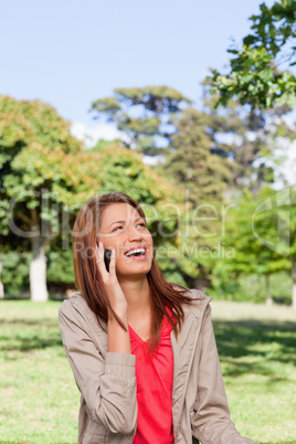Woman laughing on the phone while looking towards the sun