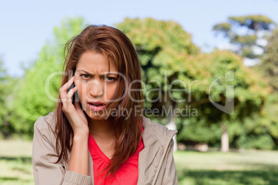 Woman with a serious expression talking on the phone in a bright