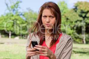 Woman with a stern expression on her face while holding a phone