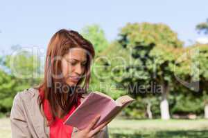 Woman reading a book in a sunny grassland area