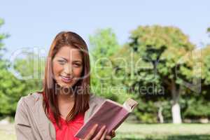 Woman smiling while looking straight ahead with a book in her ha