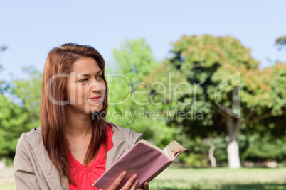 Woman smirking towards the side while reading a book