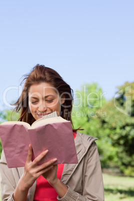 Woman happily reading a book with the wind blowing through her h