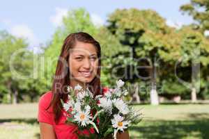 Woman looking into the distance and holding a bunch of flowers