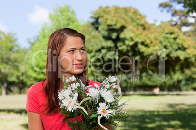 Young woman looking towards the side while holding a bunch of fl