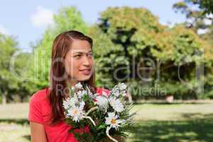 Young woman looking towards the side while holding a bunch of fl