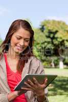 Young woman using a tablet while standing in bright park