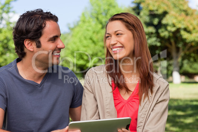 Woman looking at her friend while she is holding a tablet