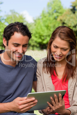 Man and his friend smiling as the watch something on a tablet