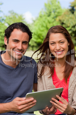 Man and a woman look ahead while holding a tablet