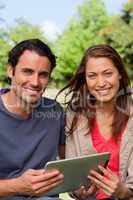 Man and a woman look ahead while holding a tablet