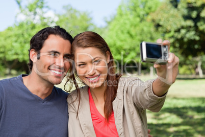 Woman takes a picture of her friend and herself with a camera