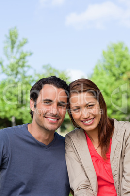 Two friends smiling as the look ahead while leaning against each