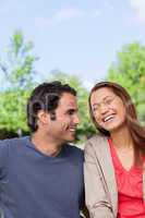 Man looking his friend as she is laughing joyfully while sitting