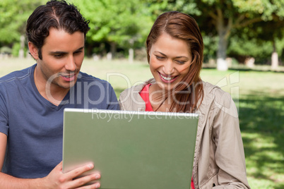Man holds a tablet as he and his friend watch something on its s