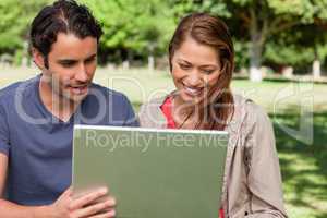 Man holds a tablet as he and his friend watch something on its s