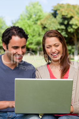 Two friends laughing as they watch something on a tablet