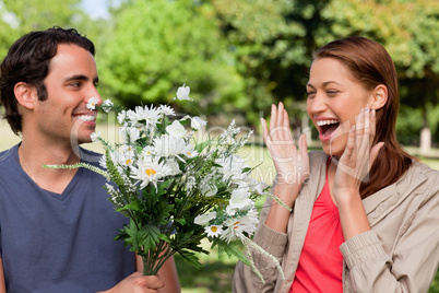 Woman laughing excitedly as she is presented with flowers by her